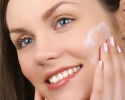 Beautiful woman applying cream to face