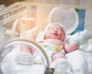 Newborn baby girl inside incubator in hospital post delivery room