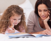 Little girl reading bedtime story with her mother