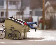 Homeless man with a bike looking in a dumpster
